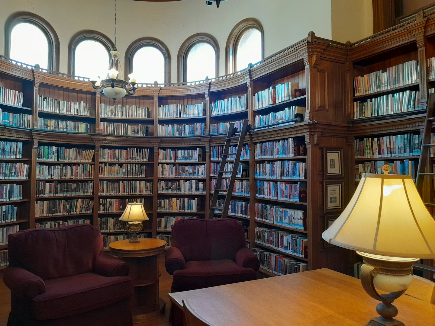 Classic library with tall wooden bookshelves and reading chairs.