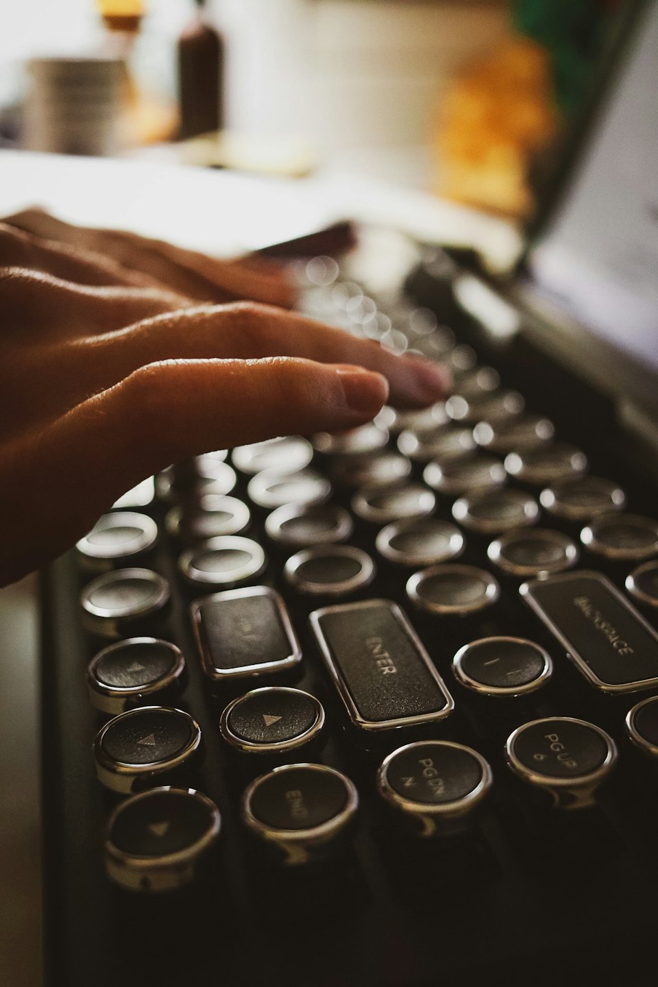 Hands typing on a retro computer keyboard with circular keys.