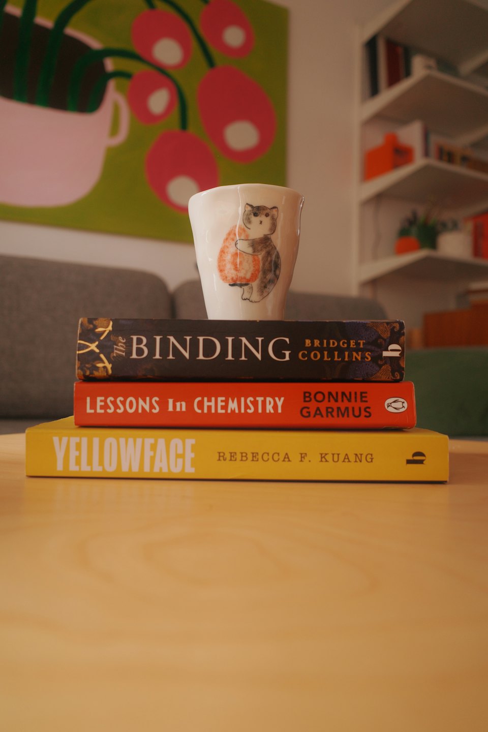 A white cat mug rests on a stack of books.